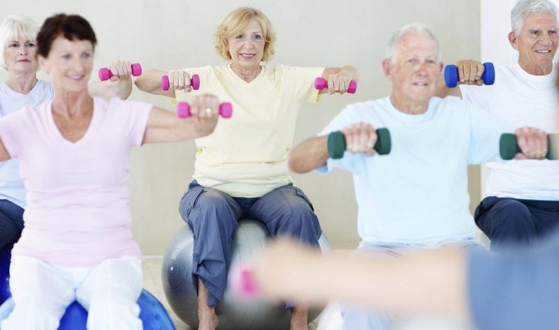 A group of elderly people lifting weights together in a fitness class